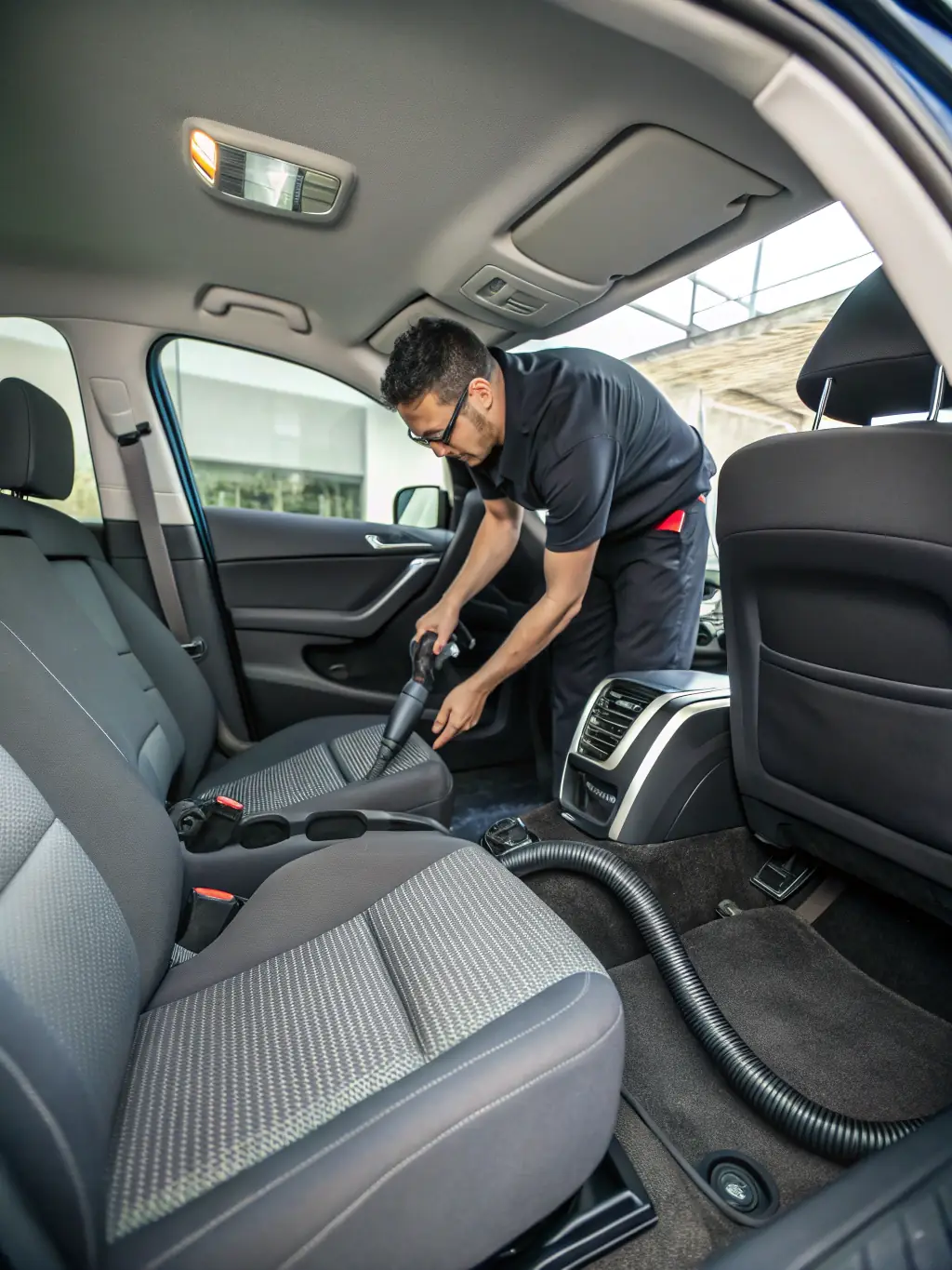 A close-up shot of a Fleet Car Wash technician meticulously cleaning the interior of a car with a vacuum cleaner, showcasing the attention to detail in interior cleaning services.